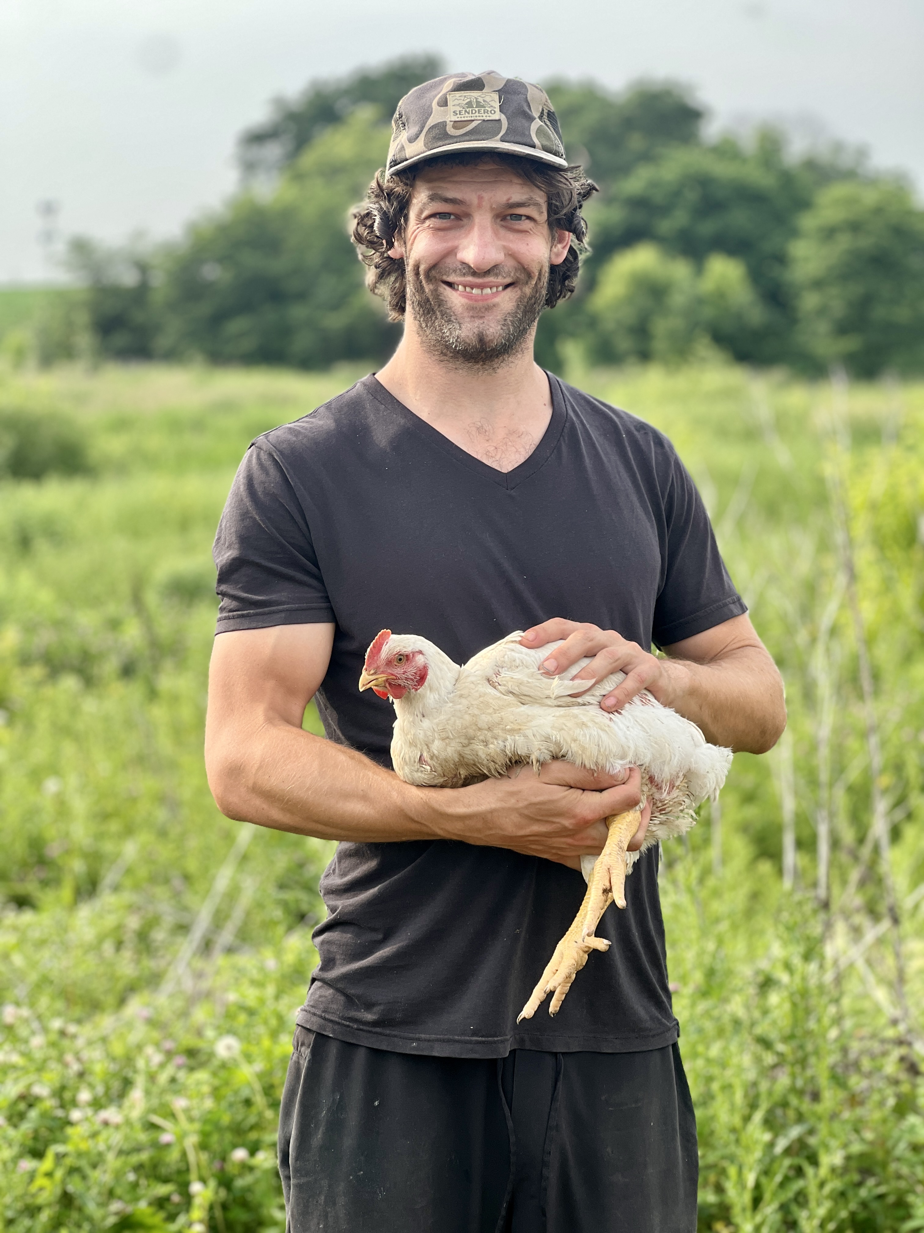 North Star Pastures farmer holding a healthy chicken on green pasture